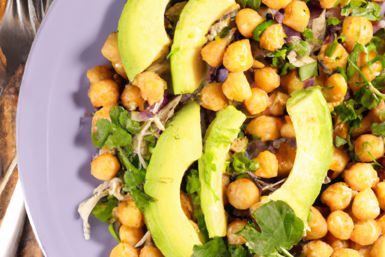 A salad with chickpeas, avocado slices, and mixed greens on a purple plate.