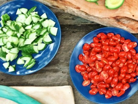 Sliced cucumber and cherry tomatoes served on blue plates.