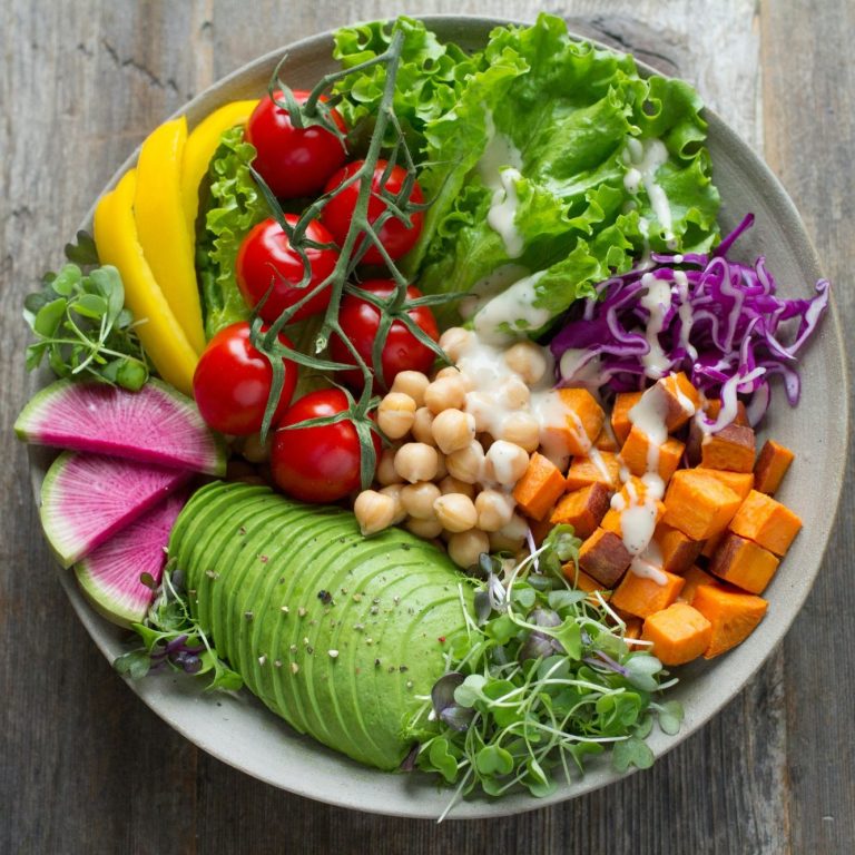 A vibrant salad bowl featuring mixed greens, cherry tomatoes, avocado, and various vegetables.