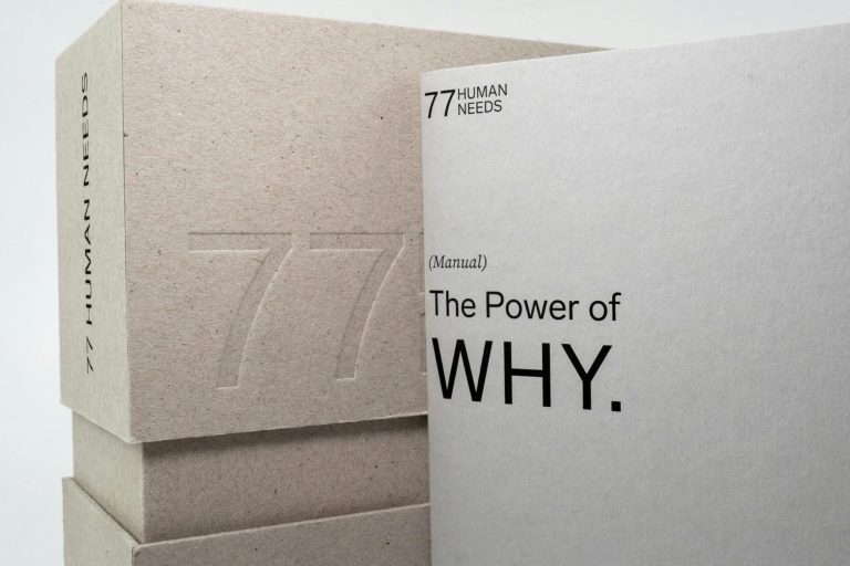 Two minimalist books, one titled "The Power of WHY", stacked on top of a textured box.